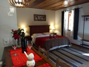 1 dormitorio con 1 cama y 1 mesa con copas de vino en Chalé Vale da Mata, en Visconde De Maua