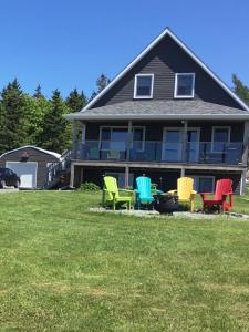 a group of colorful chairs in front of a house at BeachView Apartment in Port Hood