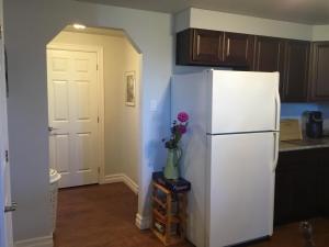 a kitchen with a white refrigerator and a vase of flowers at BeachView Apartment in Port Hood