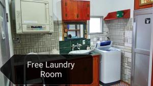 uma cozinha com uma lavandaria gratuita com um lavatório em Holiday House Ryukyu-an "MUSIC HOSTEL" em Yomitan