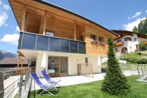 Casa con balcón y patio con sillas azules. en Klimahaus Dep. La Fradora, en San Cassiano