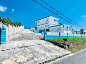 a white house with a blue fence next to a road at The Hill Inn at Arecibo 681 Ocean Drive in Arecibo