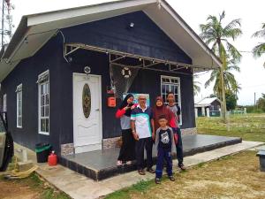 um grupo de pessoas em frente a uma casa azul em Penarik baru homestay em Kampung Penarik