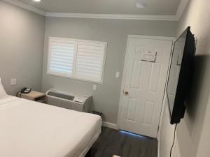 1 dormitorio con cama, ventana y puerta en Elmwood Motel, en Auburn