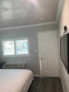 1 dormitorio con 1 cama, TV y puerta en Elmwood Motel, en Auburn