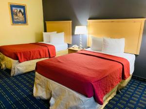 Habitación de hotel con 2 camas con sábanas rojas en Value Lodge - Gainesville, en Gainesville