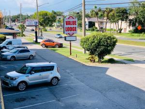 un coche aparcado en un estacionamiento junto a un cartel de motel en Value Lodge - Gainesville, en Gainesville