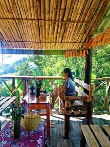 a woman sitting on a bench under a wooden roof at ChienDe Homestay in Sa Pa