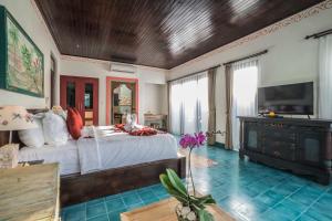 a bedroom with a large bed and a tv at Villa Tanah Carik by Mahaputra in Tegalalang