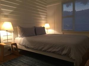 een slaapkamer met een bed met 2 lampen en een raam bij Halcyon Days in St Helens