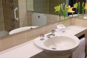 a white sink sitting under a mirror in a bathroom at Thredbo Alpine Hotel in Thredbo