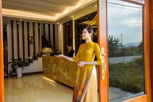 Una mujer con un vestido amarillo parada frente a una puerta en Salina Hotel Ninh Binh en Ninh Binh