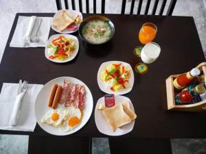 Tinna Resort في Ban Nong Mai Ngam: طاولة سوداء مع أطباق طعام الإفطار عليها