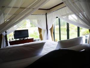 Tinna Resort في Ban Nong Mai Ngam: غرفة نوم بسرير ابيض وتلفزيون