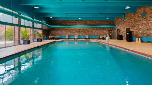 a large swimming pool in a building with blue chairs at Best Western Woodhaven Inn in Woodhaven