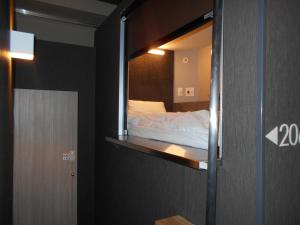 1 dormitorio con 1 cama en una habitación pequeña en BIZCOURT CABIN SUSUKINO (Male Only), en Sapporo