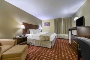 TriadelphiaにあるEcono Lodge Inn & Suites Triadelphia - Wheelingの大きなベッドとソファが備わるホテルルームです。