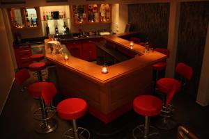 a kitchen with a bar with red stools at Hotel Engel in Emmetten