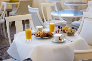 a table with a plate of food and two glasses of orange juice at Hotel Universal in Livorno