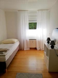 a bedroom with a bed and a window with white curtains at Ferienwohnung Mammut 1 in Salzgitter