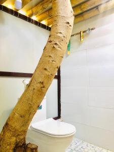 a tree trunk next to a toilet in a room at Thanh Nhi Homestay in Cam Ranh