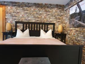 a bed with white pillows and a brick wall at Hotel Kammerkrug in Bad Harzburg