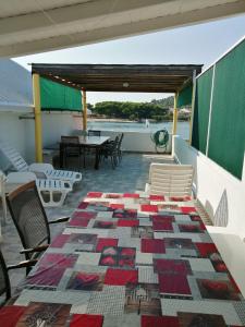 eine Terrasse mit einem Tisch, Stühlen und einer Decke in der Unterkunft Apartment with sea view terrace in Betina