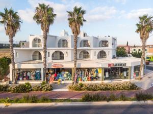 un bâtiment blanc avec des palmiers devant lui dans l'établissement Pandream Hotel Apartments, à Paphos