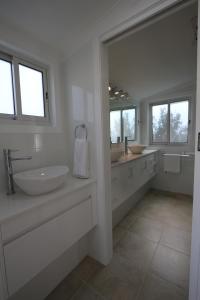 a white bathroom with two sinks and a large mirror at Moonah Central Apartments in Hobart