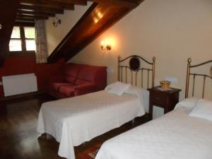 Habitación de hotel con 2 camas y sofá rojo en Apartamentos Rurales Los Villares, en Colunga