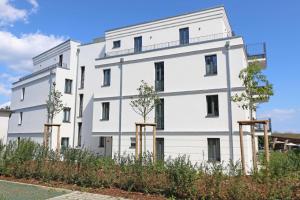 a white building with trees in front of it at Villa Düne - Ferinewohnung 07 Morgensonne in Baabe