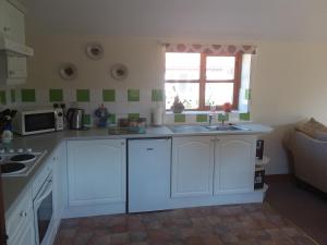 a kitchen with white cabinets and a sink and a window at Wren Cottage in Louth