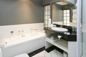 bagno con vasca, lavandino, vasca e specchio di Rosenhof Boutique Hotel a Oudtshoorn