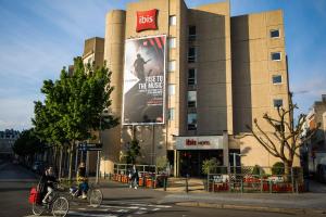 Una donna in bicicletta davanti a un palazzo di ibis Antwerpen Centrum ad Anversa