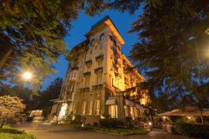 een hoog gebouw met 's nachts verlichting bij Palace Grand Hotel Varese in Varese
