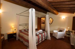 - une chambre avec un lit à baldaquin et une chaise blanche dans l'établissement I Gelsi, à Figline Valdarno