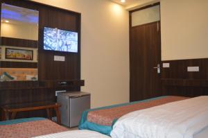 a hotel room with two beds and a flat screen tv at Cottage Ganga Inn in New Delhi