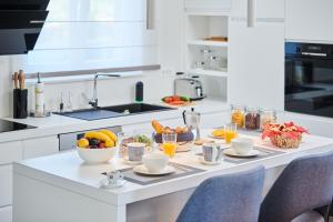 a white kitchen with a breakfast table with fruit and juice at Rainis Hill Top Villa in Oprtalj
