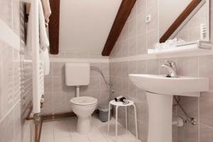 a white bathroom with a toilet and a sink at Pension Kezele in Graberje Ivanićko