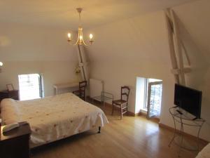 een slaapkamer met een bed en een flatscreen-tv bij Le Relais de la Tour in Figeac