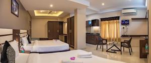 a hotel room with two beds and a kitchen at Aadya Elite in Mysore