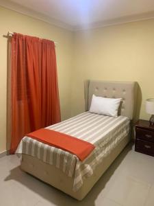 1 dormitorio con 1 cama con cortina naranja en Cozy 2br-2bt Apt Near The Beach And Main Street, en Sosúa