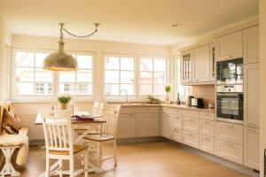 a kitchen with white cabinets and a table and chairs at Grüne Hufe in Born