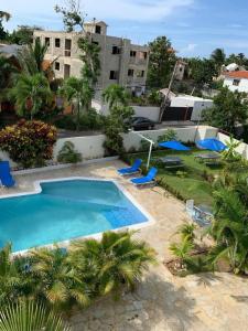 una gran piscina con sillas azules y palmeras en Cozy 2br-2bt Apt Near The Beach And Main Street, en Sosúa