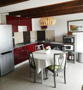 una cucina con armadi rossi e un tavolo con sedie di au pied de l'Ile Oléron a Bourcefranc