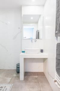 biała łazienka z umywalką i lustrem w obiekcie Modern White Tower Apartment w Salonikach