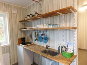 a kitchen with a sink and wooden shelves at Drottning Ödas Boende in Degerhamn