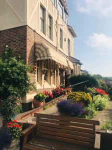 a building with flowers and a bench in front of it at The Bebington in Bebington