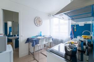 a blue and white kitchen with a table and a clock at Le Studio Bleu de la gare in Vieux-Boucau-les-Bains