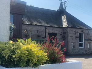 an old stone building with flowers in front of it at The 1645 Inn in Nairn